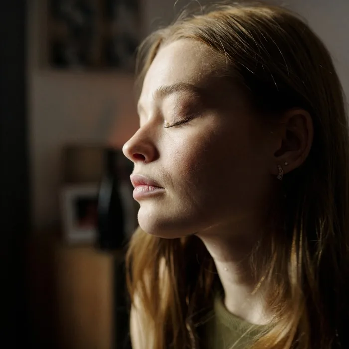 A woman with her eyes closed in warm light, a quiet internal moment