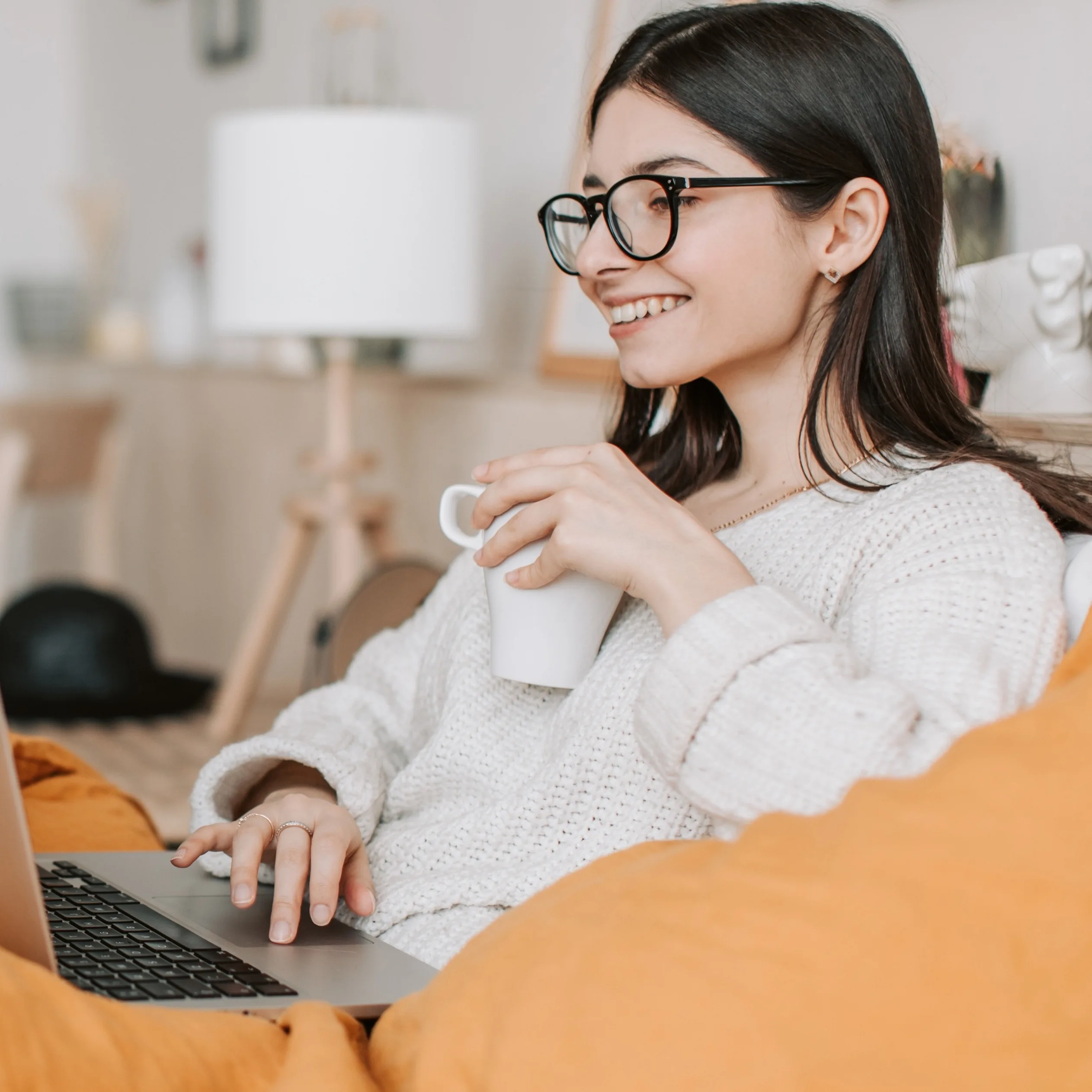 Smiling over coffee while working on a laptop