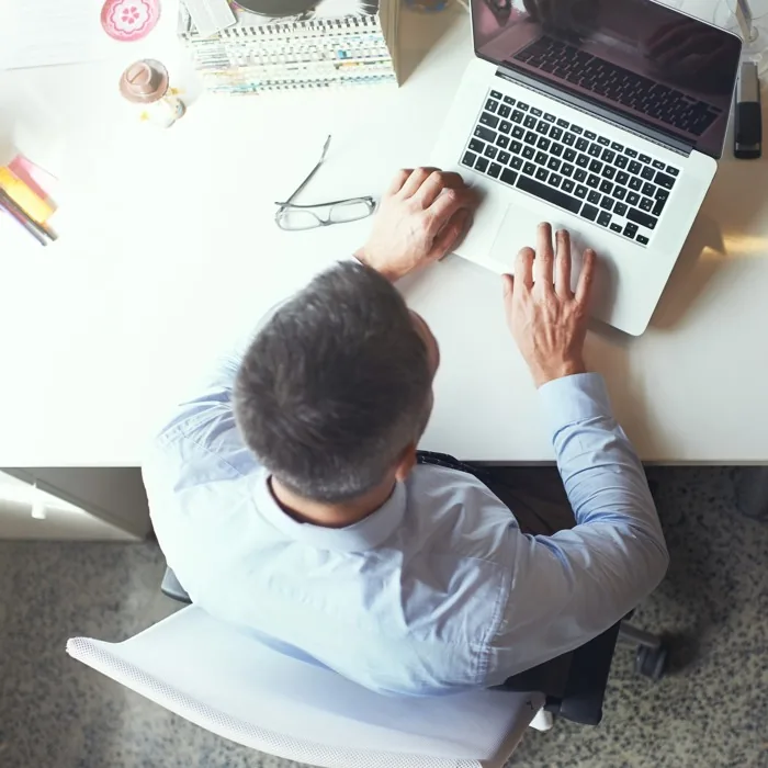 A man working at his laptop, overhead desk view